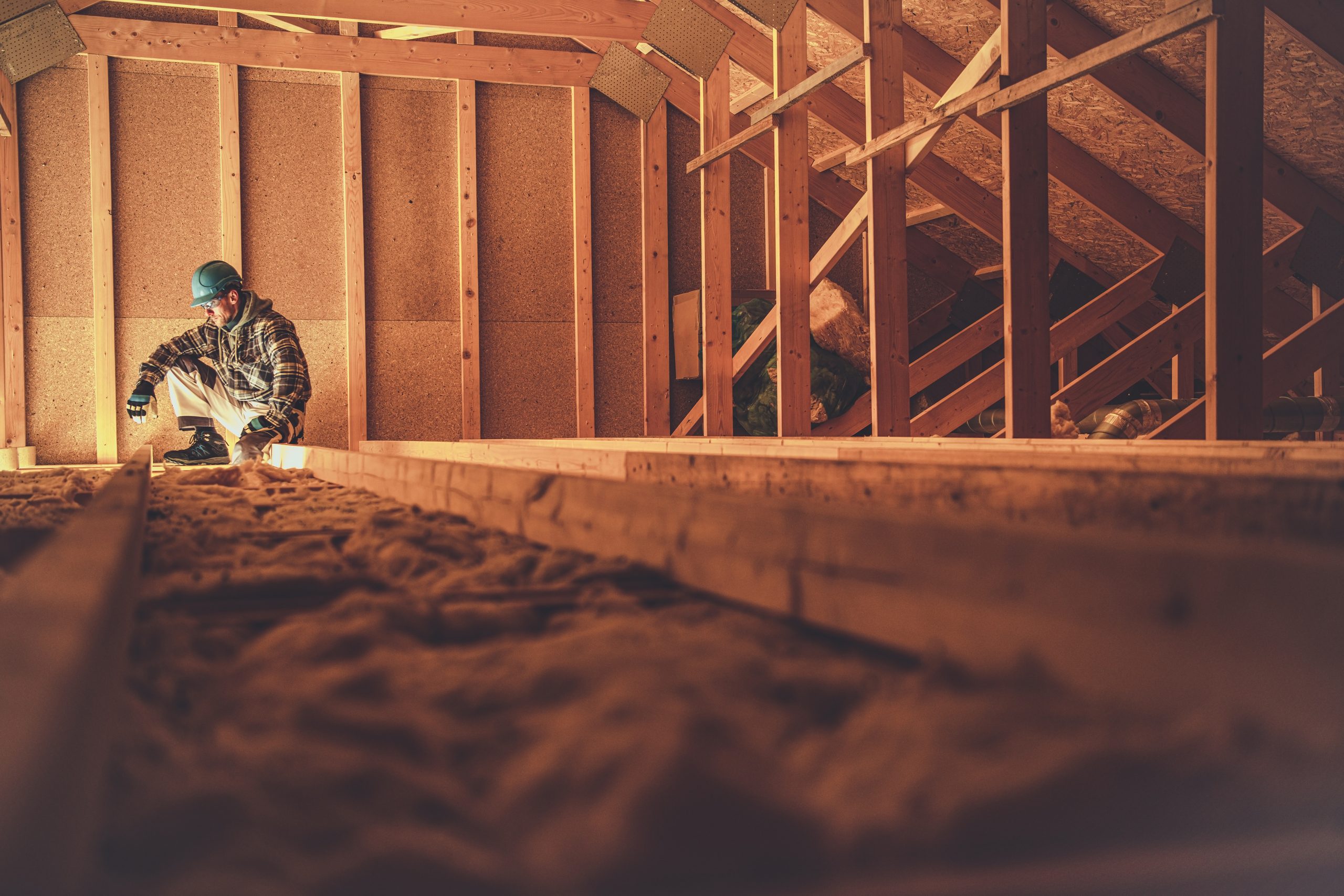 Stavebný špecialista aplikuje fúkanú derevovláknitú izoláciu počas stavby montovaného drevodomu