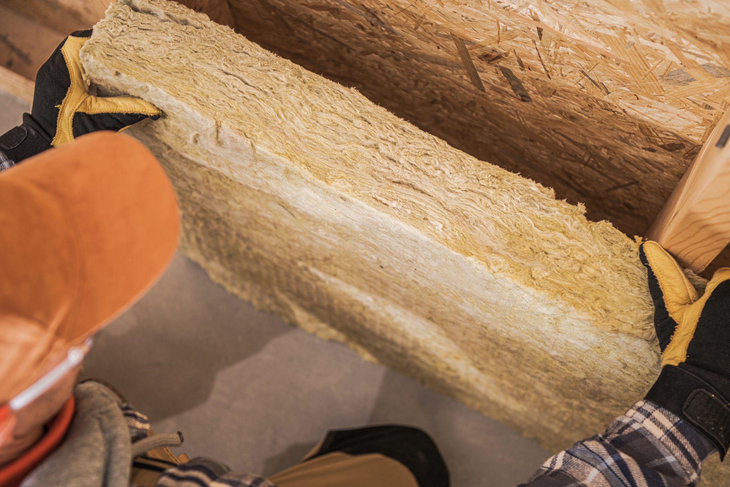 Stavebný špecialista drží plát fúkanej drevovláknitej izolácie počas stavby montovaného drevodomu