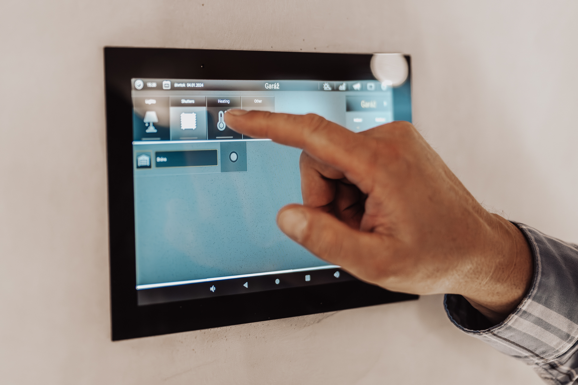 Ovládací tablet pre inteligentnú domácnosť zabudovaný v stene s rukou nastavujúcou teplotu v garáži montovaného drevodomu