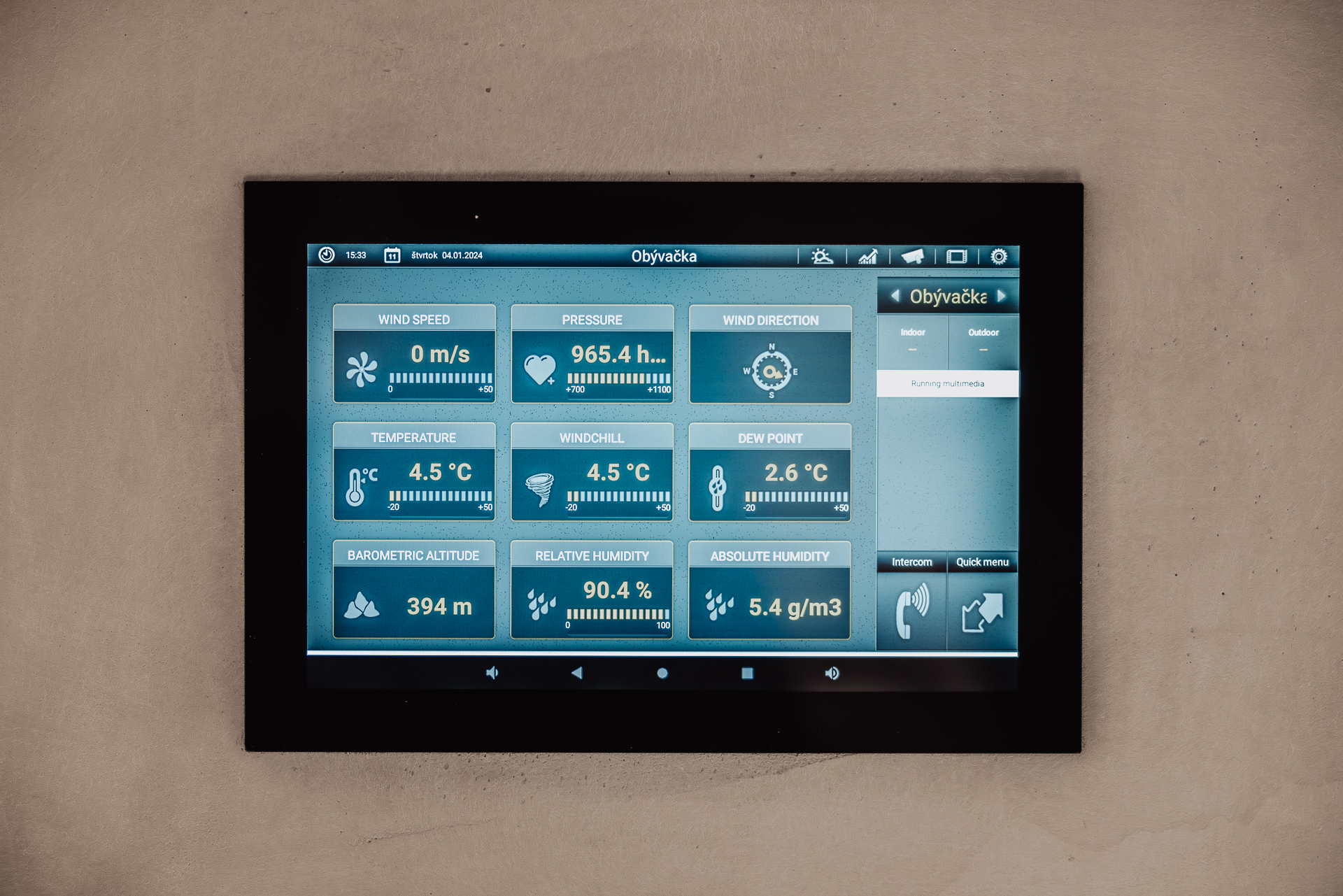 Ovládací tablet pre inteligentnú domácnosť zabudovaný v stene s údajmi o teplote, tlaku a vlhkosti v interiéri a exteriéri
